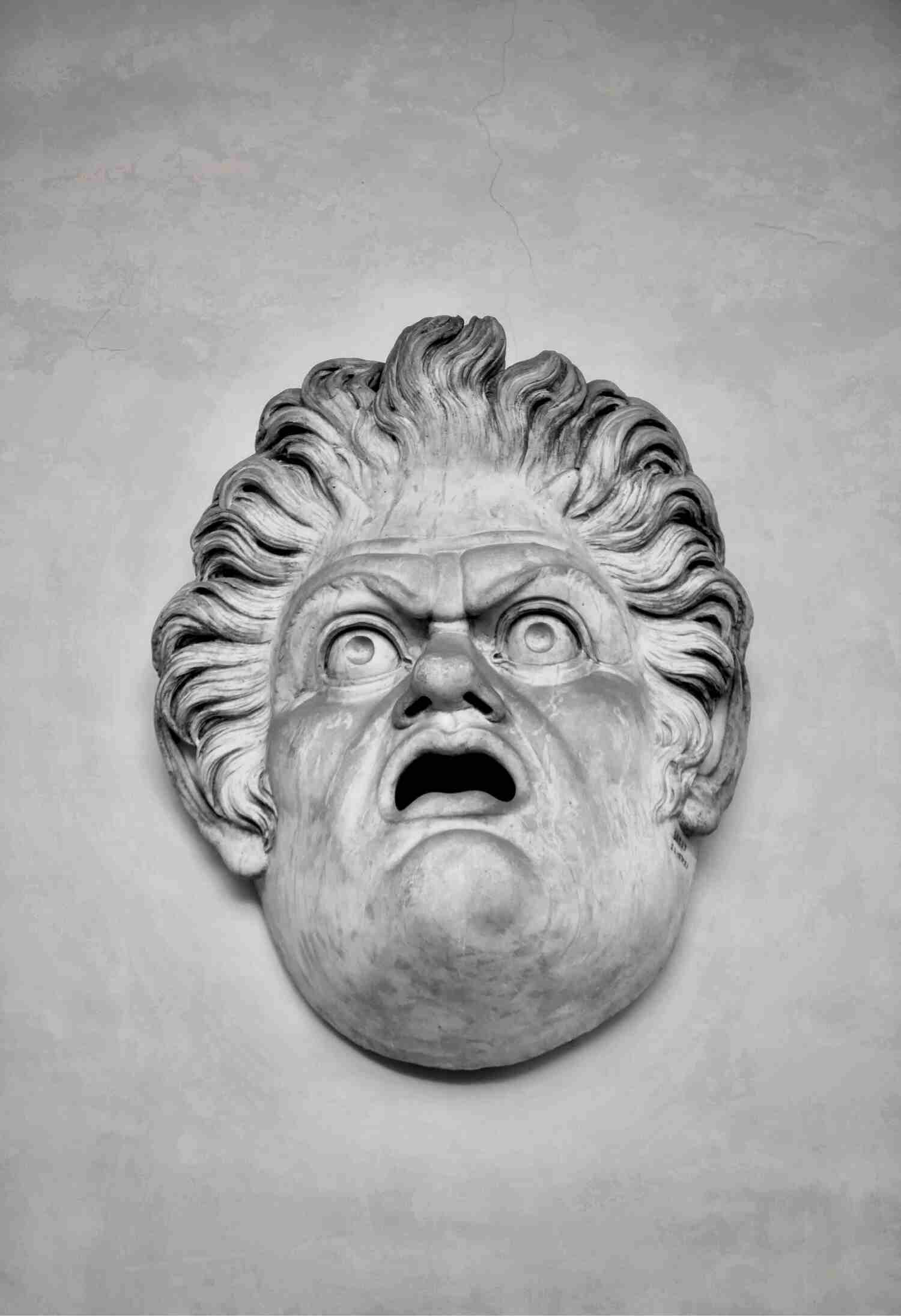 A sculpture of an expressive figure with long, wavy hair, looking upwards with wide, shocked eyes and open mouthed